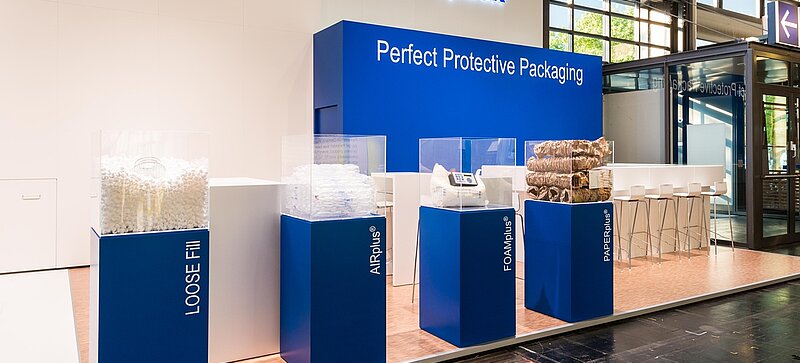 
	  Un estand de feria de Storopack con cuatro vitrinas azules