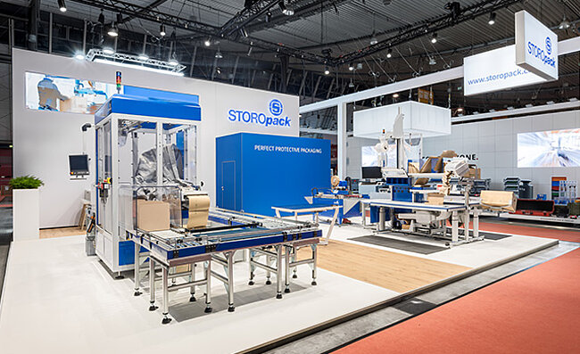 Un estand de feria de Storopack con cuatro vitrinas azules