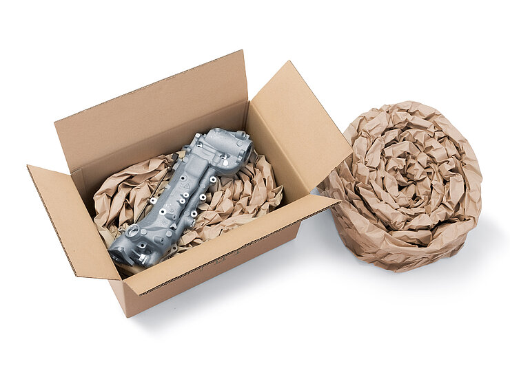 Una caja de cartón que contiene un componente y almohadillados de papel hechos con tiras de almohadillados de papel enrolladas