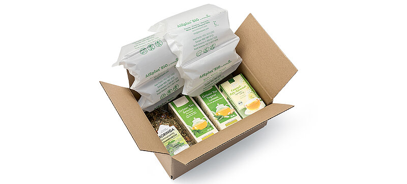 Una caja de cartón con paquetes de té y acolchado de aire orgánico