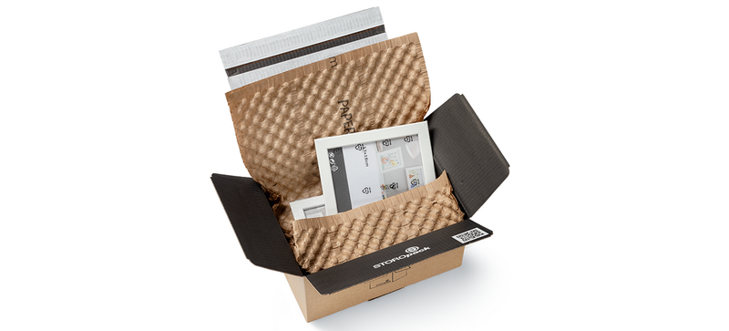 Una caja de cartón con marcos de fotos envuelta en hojas de papel de burbujas marrón