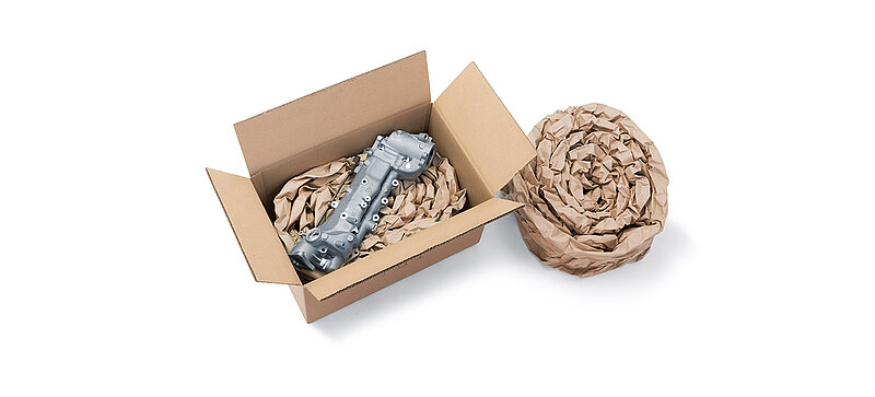 Una caja de cartón que contiene un componente y almohadillados de papel hechos con tiras de almohadillados de papel enrolladas