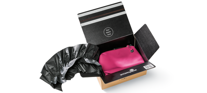 Una caja de cartón que contiene una bolsa rosa y almohadillados de papel negro