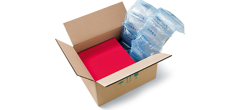 Una caja de cartón que contiene una caja roja y acolchado de aire 100 % reciclado