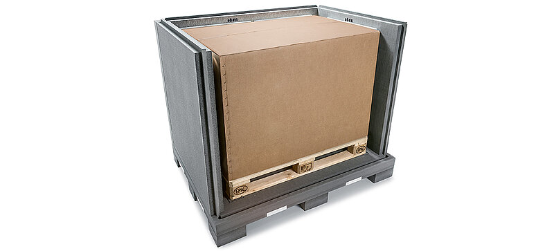 Un contenedor aislante negro con una caja de cartón interior y baterías de refrigeración en un palé 