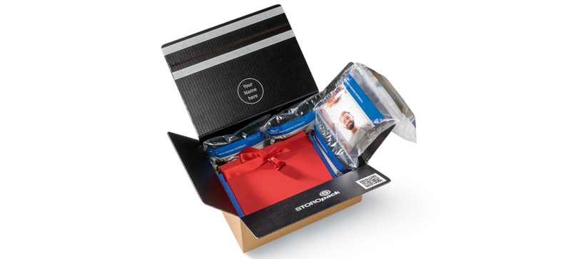 Una caja de cartón que contiene una caja de regalo roja y acolchado de aire con un diseño impreso